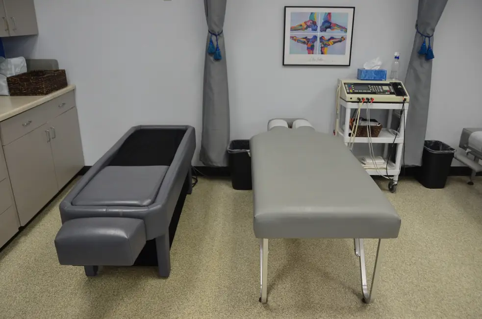 Treatment room at Aascend Chiropractic in Appleton, with two treatment tables, a Dynatron electrotherapy unit and framed anatomical prints